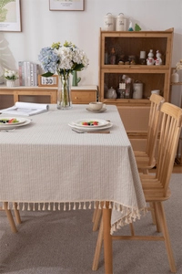 Detailed view of beige cotton tablecloth featuring geometric stripes and fringe tassels