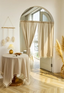 Detail of cotton linen door curtain with tassel edges and striped pattern in warm sunlight