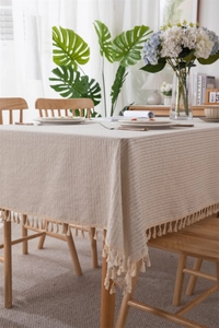 Detail of cotton linen tablecloth with white vertical stripes and fringe tassels decoration