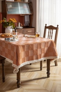 Détail de nappe jacquard géométrique rouge et crème avec des franges à glands
