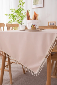 Detailed view of pale pink waterproof PVC tablecloth with decorative white tassels edges