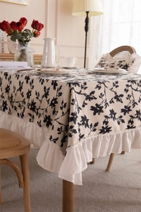 Detail of French floral tablecloth with ruffled edges and black botanical print