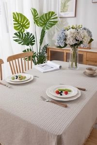 Detail of beige geometric jacquard tablecloth with vertical stripes and tassel fringe