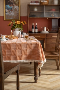Détail de nappe à carreaux orange et blanc avec pompons et texture nid d'abeille