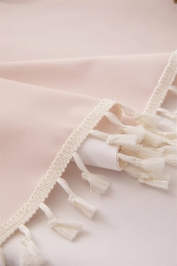 Detail of peach PVC tablecloth with waterproof texture and white tassel fringe edges