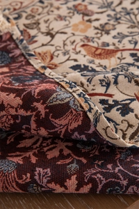 Macro detail of vintage jacquard fabric featuring floral and bird patterns with tassels