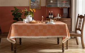 Détail macro de la nappe jacquard à carreaux orange avec des franges à pompons