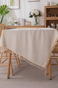 Close-up of beige jacquard cotton tablecloth with vertical stripes and tassel trim