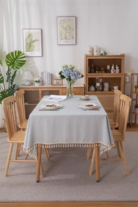 Close-up of blue striped cotton tablecloth with elegant beige fringe tassels and texture
