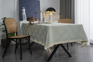 Gros plan d'une nappe jacquard vert sauge à damier avec des pompons de franges crème