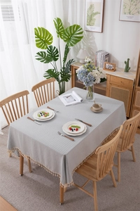 Close-up of light gray cotton tablecloth with white stripes and elegant tassel fringe details