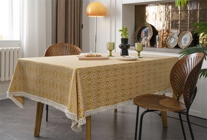 Detalle del mantel jacquard amarillo con patrón geométrico y bordes de flecos blancos