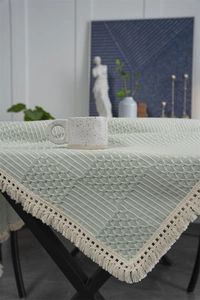 Détail d'une nappe vert clair à tissage gaufré avec bords à franges et maille