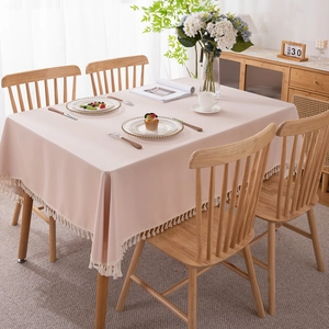 Pink waterproof PVC tablecloth with white tassel edge on a wooden dining table