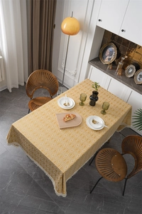 Detalle de mantel amarillo mostaza con rombos geométricos y flecos tejidos suaves