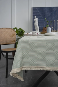 Détail d'une nappe en jacquard vert sauge avec texture géométrique et pompons crème