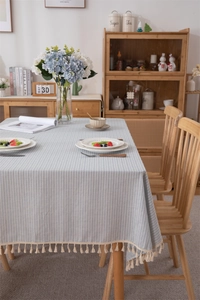 Close-up of light blue striped cotton tablecloth with elegant cream fringe tassels