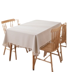 Rectangle cream PVC tablecloth with decorative fringe tassels on a wooden dining table