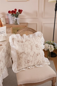 Close-up of floral print pillow with decorative ruffled edges on a vintage chair
