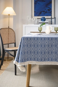 Detalle del mantel geométrico de rombos azul y blanco con elegantes borlas de color crema