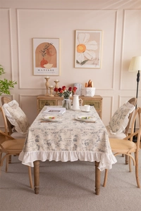 Detail of French floral tablecloth with blue botanical print and white ruffled edges