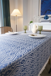 Detalle del mantel geométrico azul y blanco con elegantes flecos de algodón en los bordes