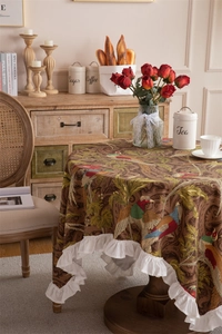 Detail of vintage floral cotton tablecloth featuring bird print and ruffled lace edges