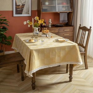 Nappe géométrique moderne à carreaux jaunes avec glands sur une table à manger rectangulaire