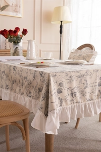 Detail of French floral print tablecloth featuring elegant ruffled edges and linen texture