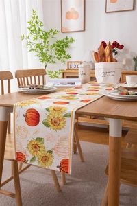 Detailed view of fall harvest table runner with pumpkin and sunflower prints on wood table