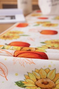 Detail of harvest pumpkin and sunflower print on textured linen Thanksgiving table runner
