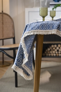 Detalle de los patrones geométricos jacquard y borlas de flecos en el mantel azul y blanco