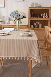 Detail of beige jacquard cotton tablecloth with striped texture and elegant fringe edge