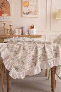 Detailed close-up of floral polyester tablecloth with ruffled edges on wooden table