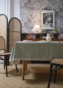 Detalle de mantel de jacquard geométrico con bordes de flecos en verde y beige