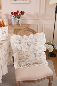 Close-up of floral print square pillow with elegant ruffle edges on vintage chair