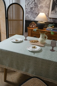 Primer plano del mantel de jacquard geométrico en verde retro con borlas decorativas crema