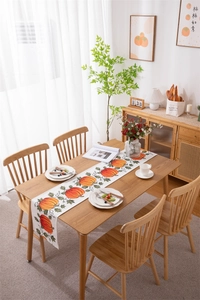 Close-up of Thanksgiving table runner with vibrant orange pumpkins and green leaves print