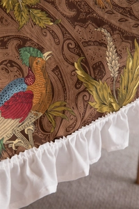 Close-up of vintage cotton tablecloth featuring pheasant print and white ruffled edge