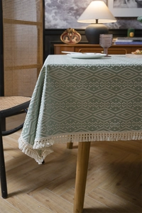 Detalle de mantel de jacquard verde salvia con rombos geométricos y elegantes flecos