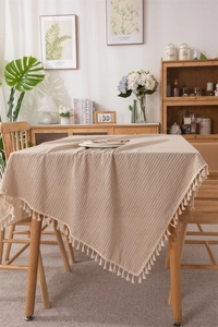Detailed view of beige cotton jacquard tablecloth with vertical stripes and tassel edges