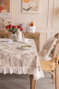 Detail of floral printed tablecloth with elegant ruffled edges in a cozy French setting