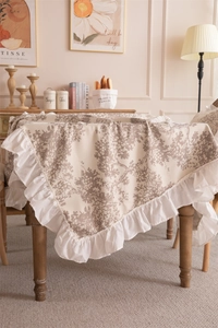 Detail of French floral print tablecloth with elegant ruffled edges in a rustic home setting
