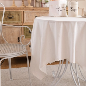 Tovaglia minimalista in cotone lavato bianco con drappeggio naturale su tavolo tondo