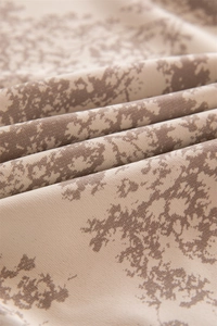 Detail of French floral tablecloth showing soft beige fabric texture and dark brown print