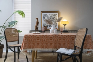 Primer plano del mantel de jacquard geométrico naranja con flecos de borlas blanco crema