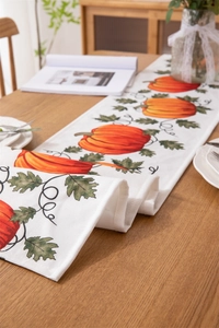 Close-up of harvest pumpkin pattern on linen table runner with autumn floral decor