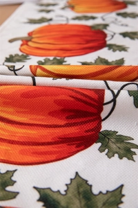 Macro detail of pumpkin and maple leaf print on textured polyester-cotton autumn table runner