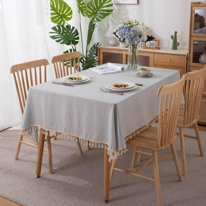Blue striped cotton jacquard tablecloth with fringes on a wooden table, 45-degree view