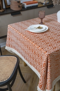 Detalle de mantel jacquard geométrico con elegantes bordes de flecos de borlas blancas